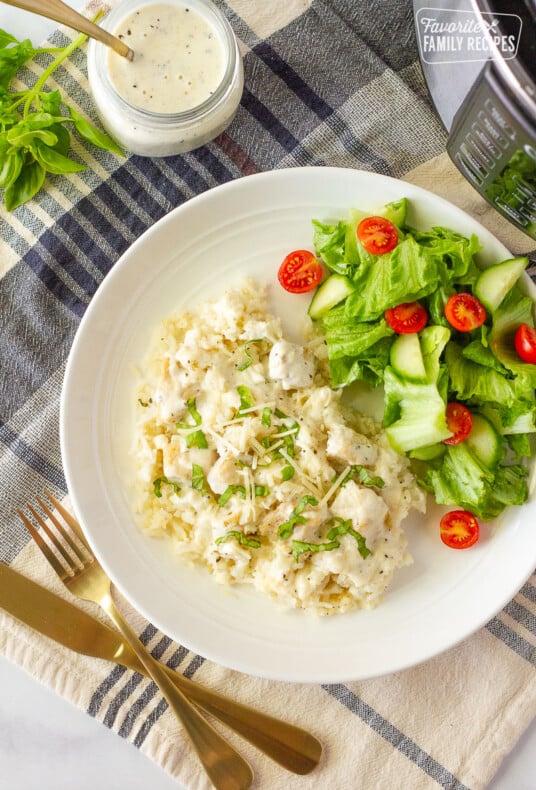 Top view of Instant Pot Chicken and Rice with silverware on the side. Green salad served on the side.