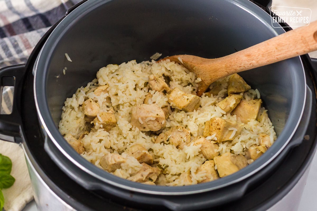 Instant Pot with wooden spoon stirring the cooked Rice and Chicken.