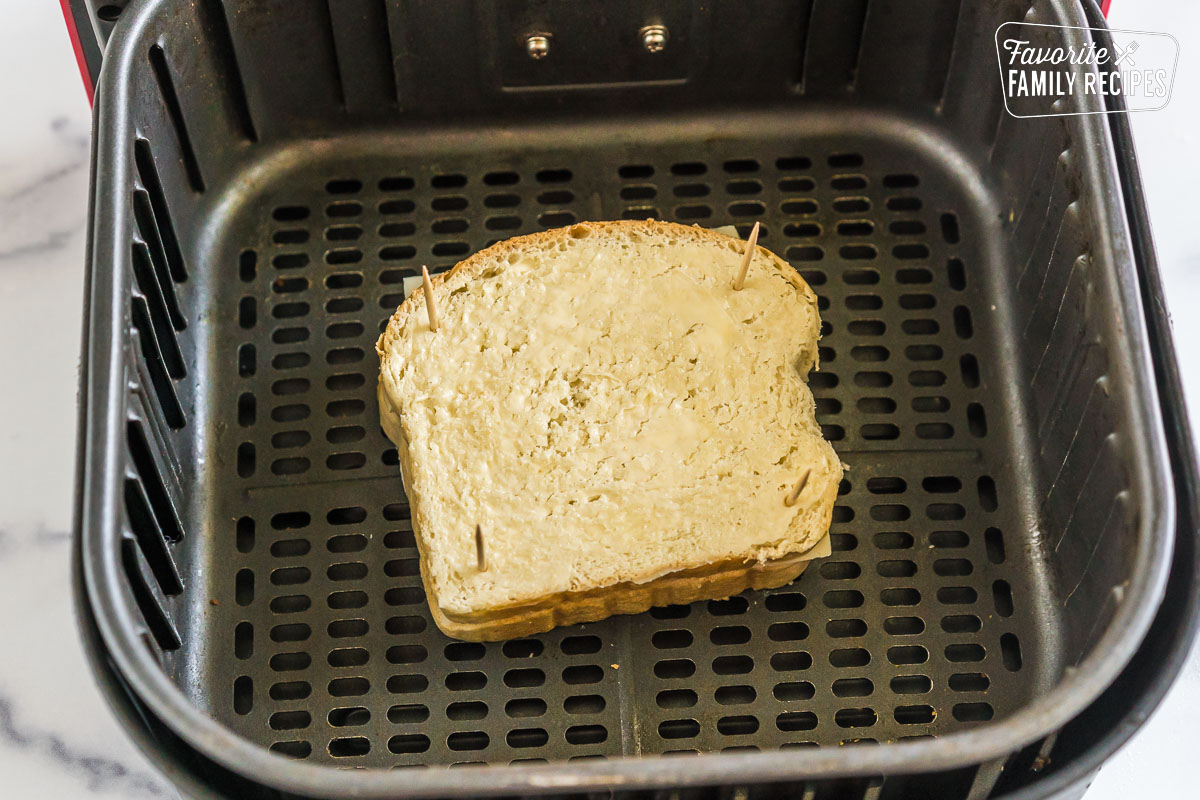A grilled cheese sandwich in an air fryer basket before it is cooked