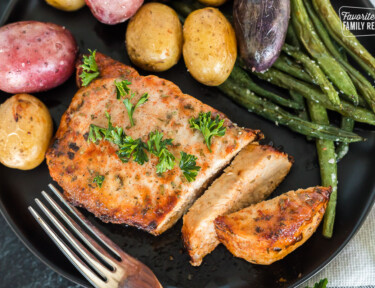 A top view of a pork chop made in the air fryer on a plate with vegetables