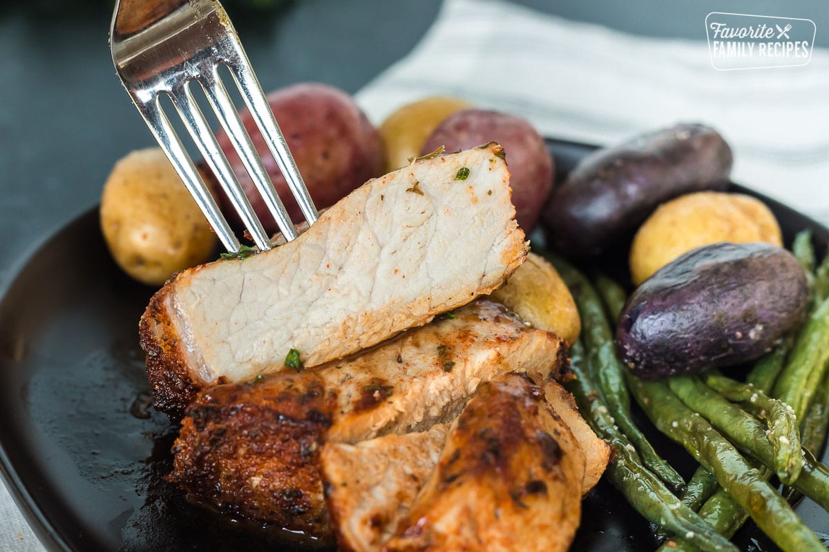 An air fryer pork chop cut in half to show juicy texture inside.