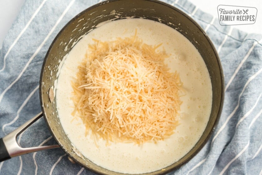 Cream and butter melted in a sauce pan with fresh Parmesan being melted in