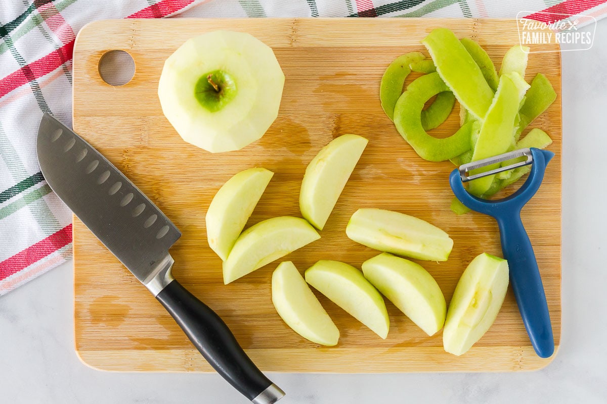 Cutting board with peels and sliced green apples for Apple Dumplings.