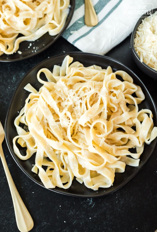 Fettuccine Alfredo on a plate next to a gold fork
