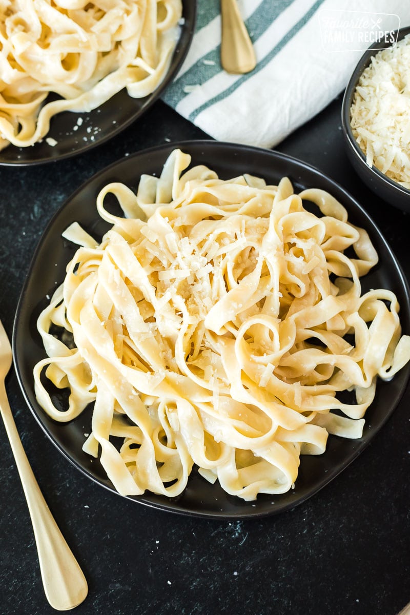 Fettuccine Alfredo on a plate next to a gold fork