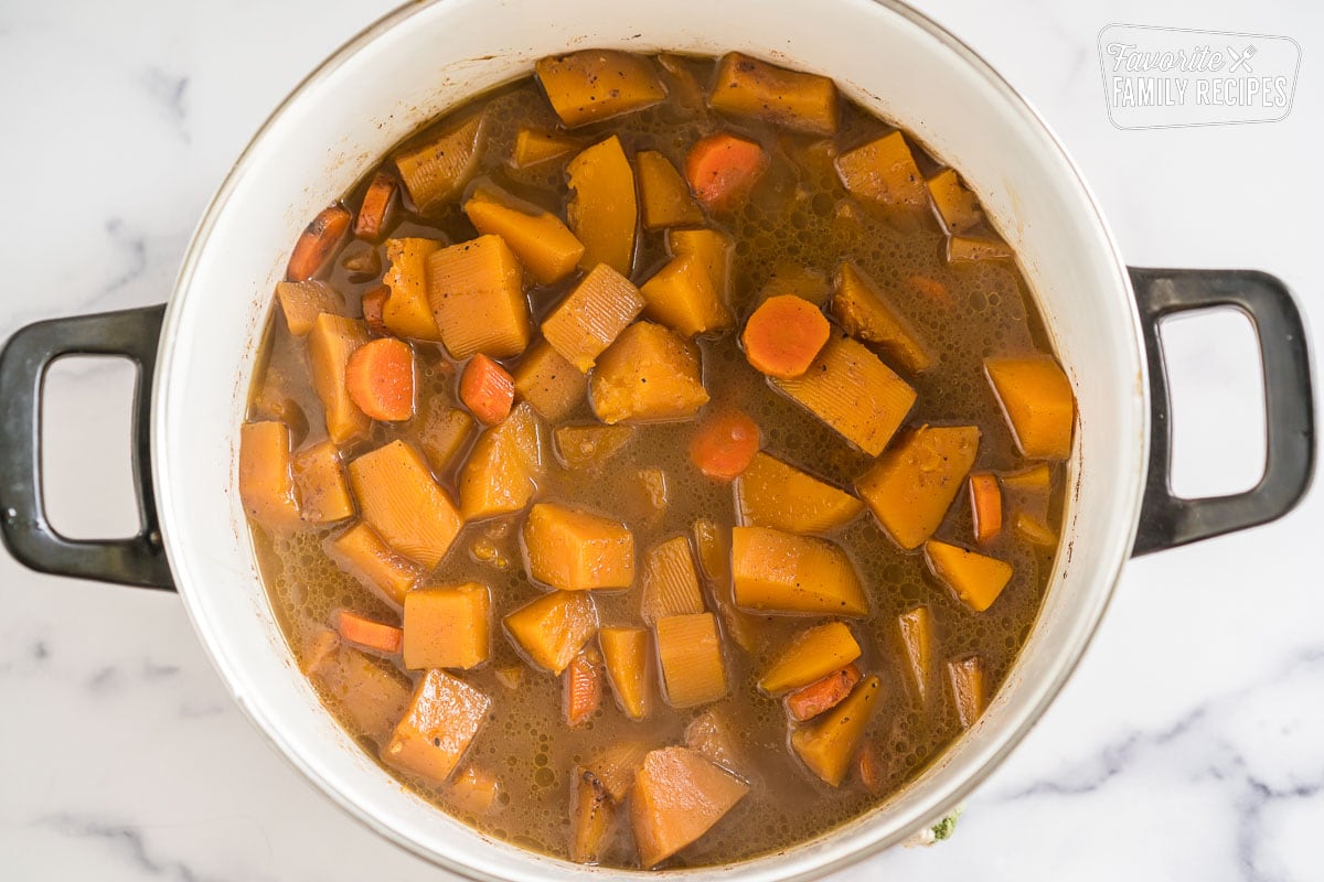 A large pot of butternut squash and carrots simmering in broth.