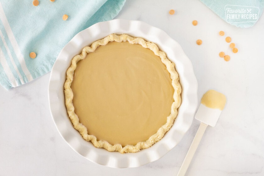 Butterscotch Pie filling in a pie crust without the toppings. Spatula on the side.