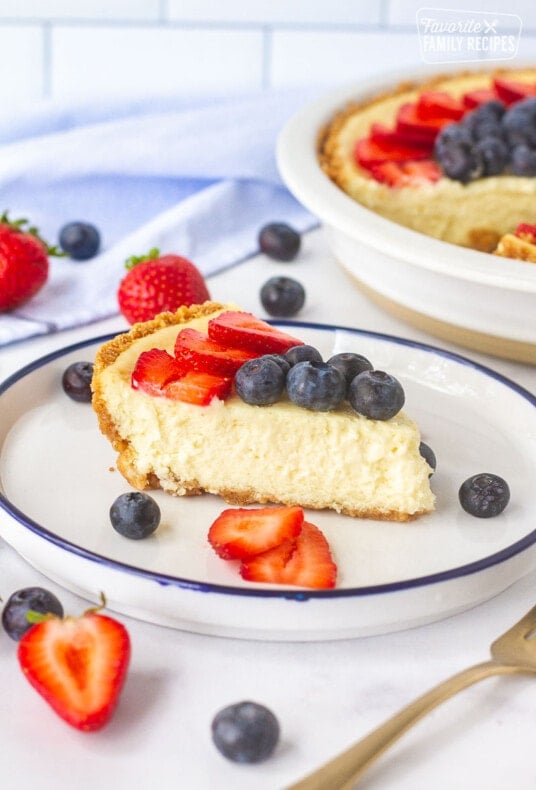 Side view of a cheesecake slice to show How to Make a Cheesecake decorated with fresh strawberries and blueberries.