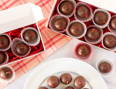 Gift boxes of Chocolate Covered Cherries and a plate of Chocolate Covered Cherries.