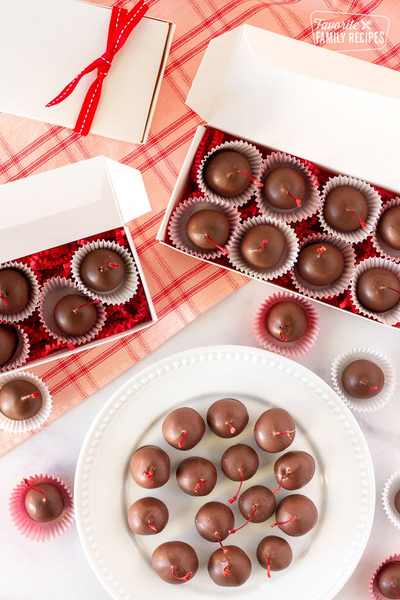 Gift boxes of Chocolate Covered Cherries and a plate of Chocolate Covered Cherries.