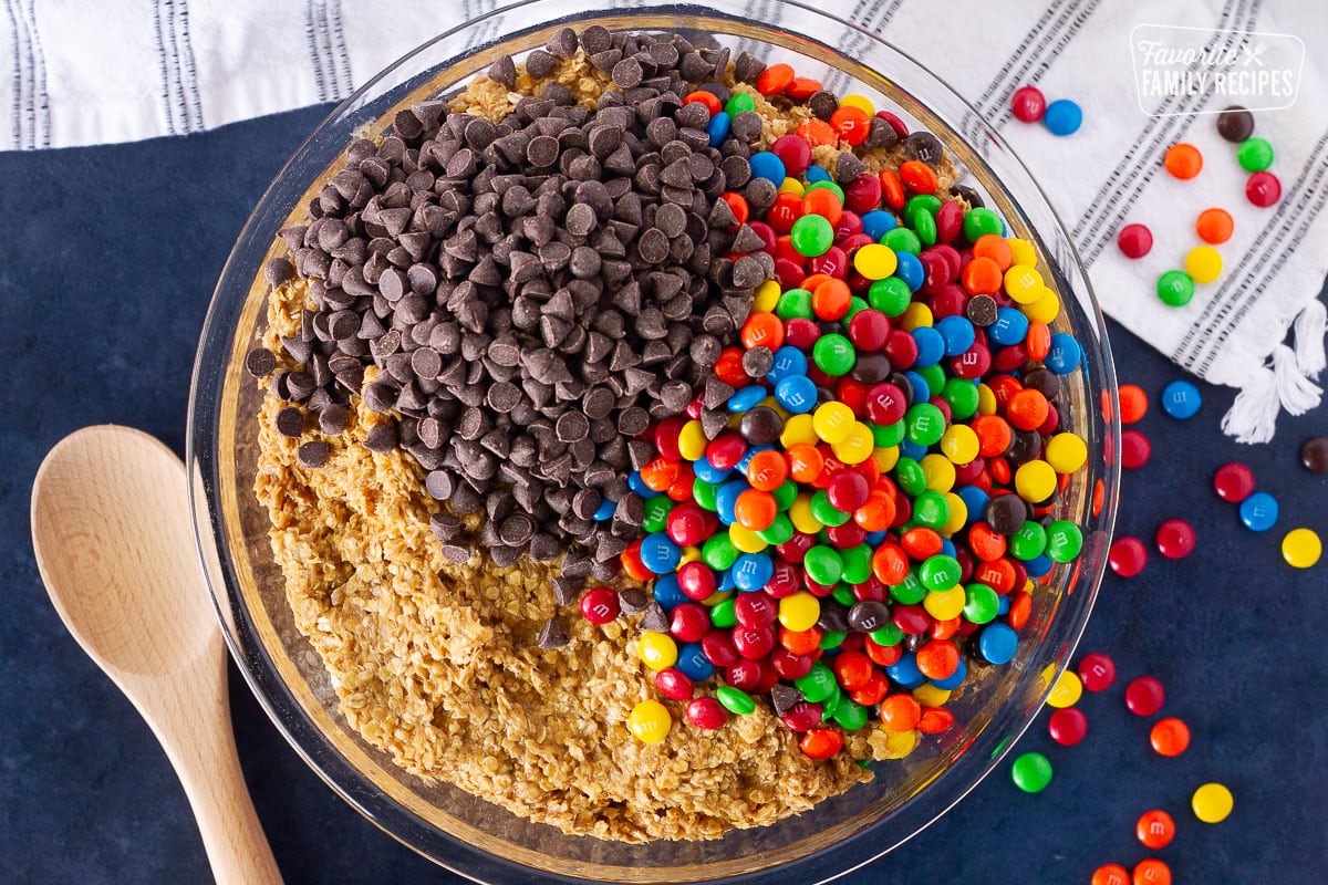 Bowl of Monster Cookie dough with unmixed chocolate chips and M&Ms on top.