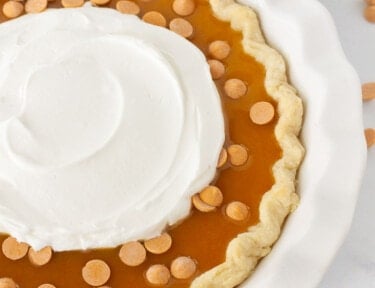 Close up of Butterscotch Pie with butterscotch syrup, chips and whipped cream.