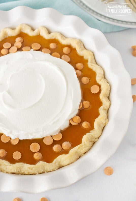 Close up of Butterscotch Pie with butterscotch syrup, chips and whipped cream.