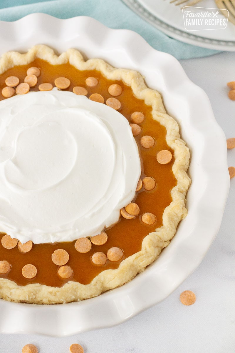 Close up of Butterscotch Pie with butterscotch syrup, chips and whipped cream.