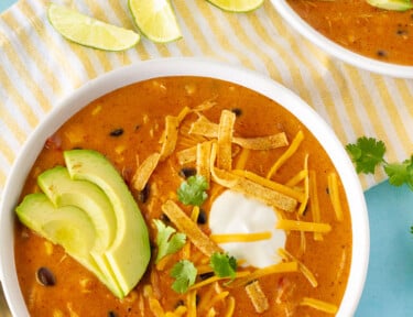 Top view of Cafe Zupas Chicken Enchilada Chili garnished with avocado, cheese, cilantro, chips and sour cream.