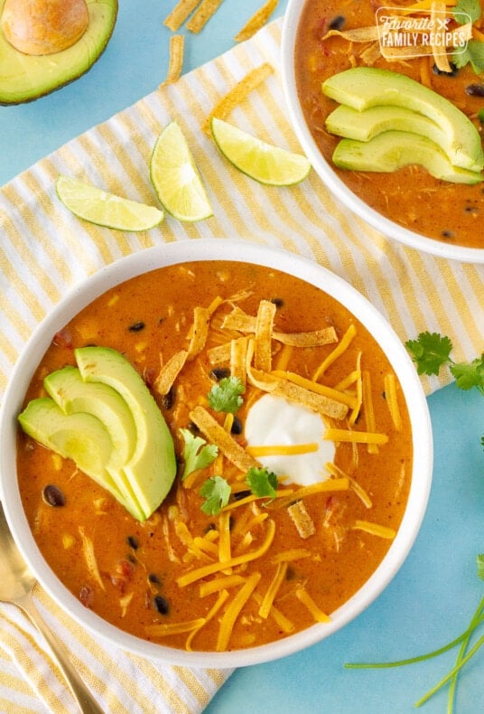 Top view of Cafe Zupas Chicken Enchilada Chili garnished with avocado, cheese, cilantro, chips and sour cream.