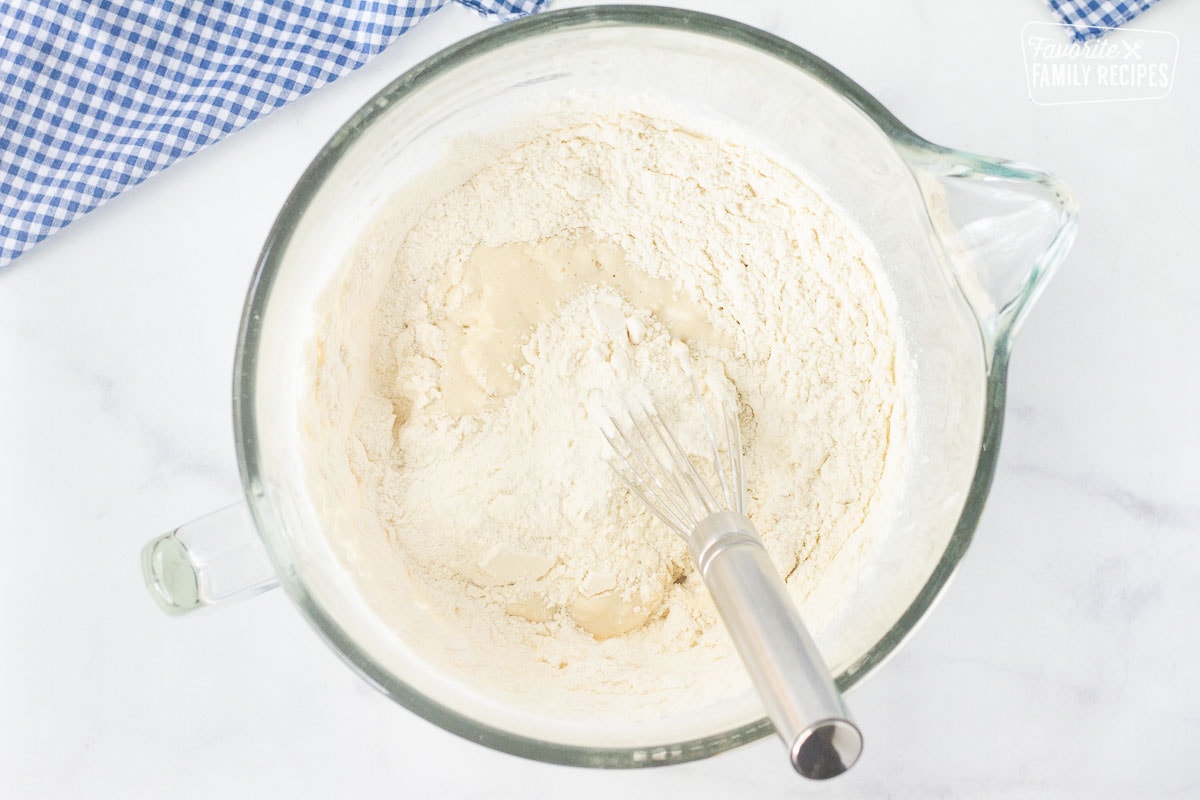 Bowl of wet ingredients and dry ingredients combined with a whisk to make Subway Bread dough.