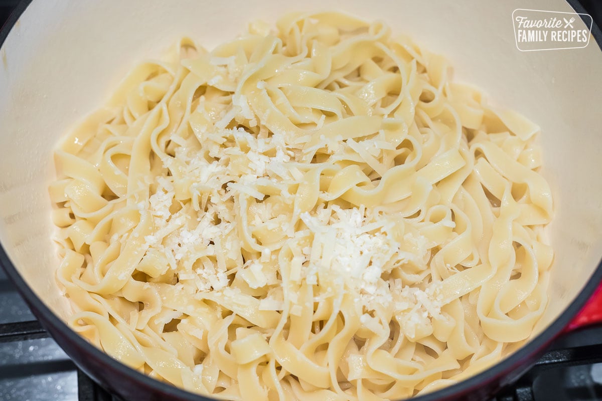Fettuccine noodles in a pot with parmesan cheese sprinkled over the top