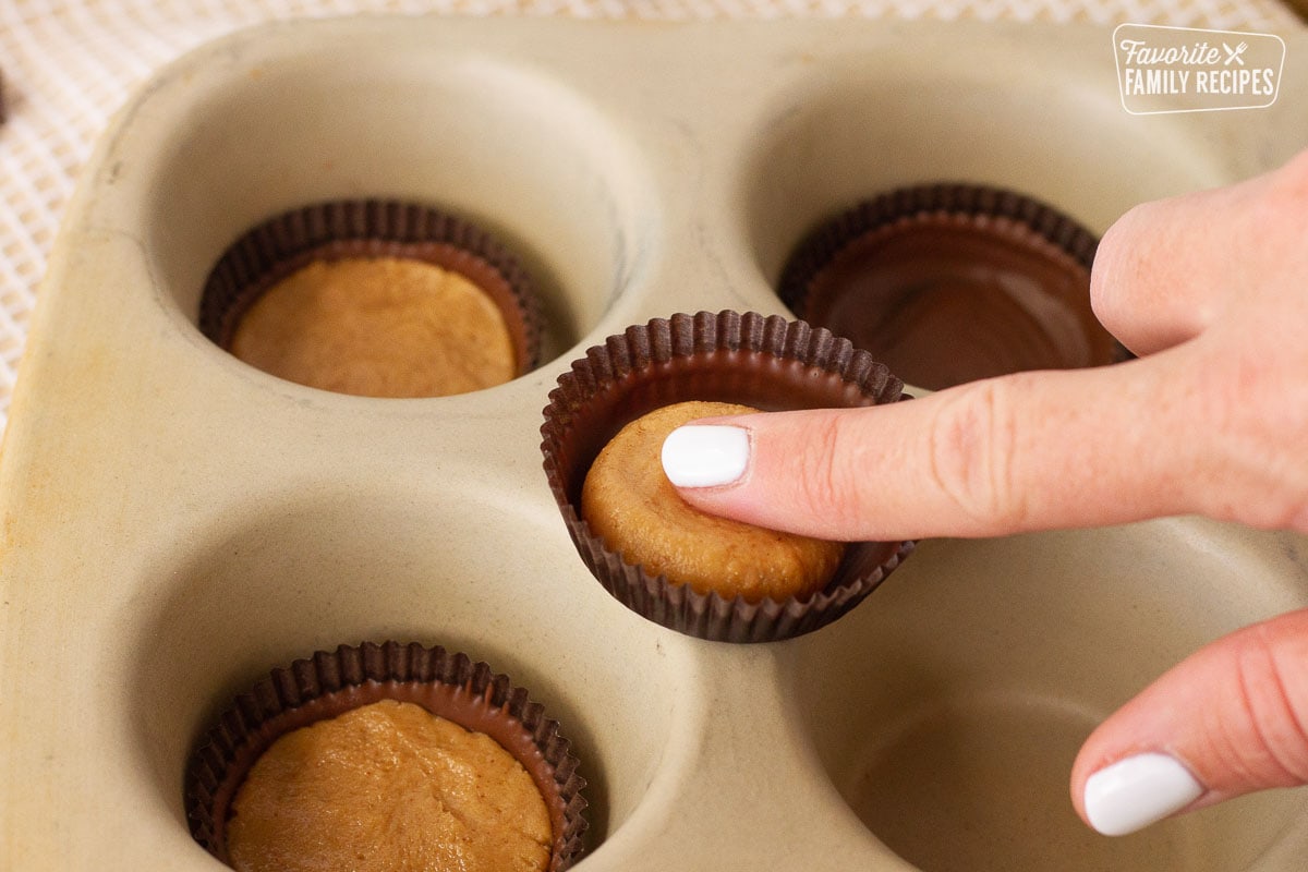 Finger pressing down the filling into the liner for Homemade Reese's Peanut Butter Cups.