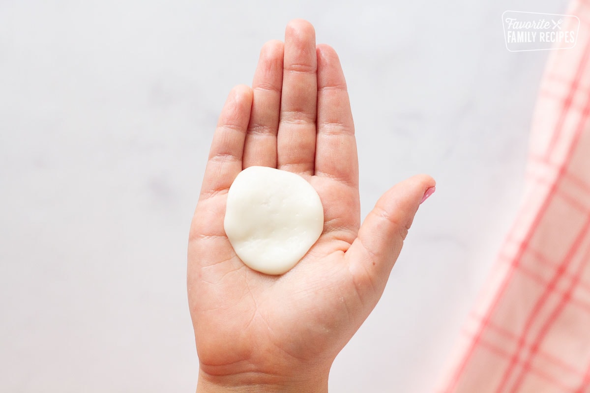 Hand holding flattened circle of fondant for Chocolate Covered Cherries.