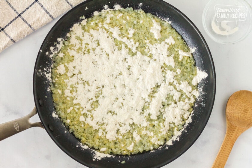 Flour added to pan of onions, garlic and butter to make Creamed Spinach sauce.
