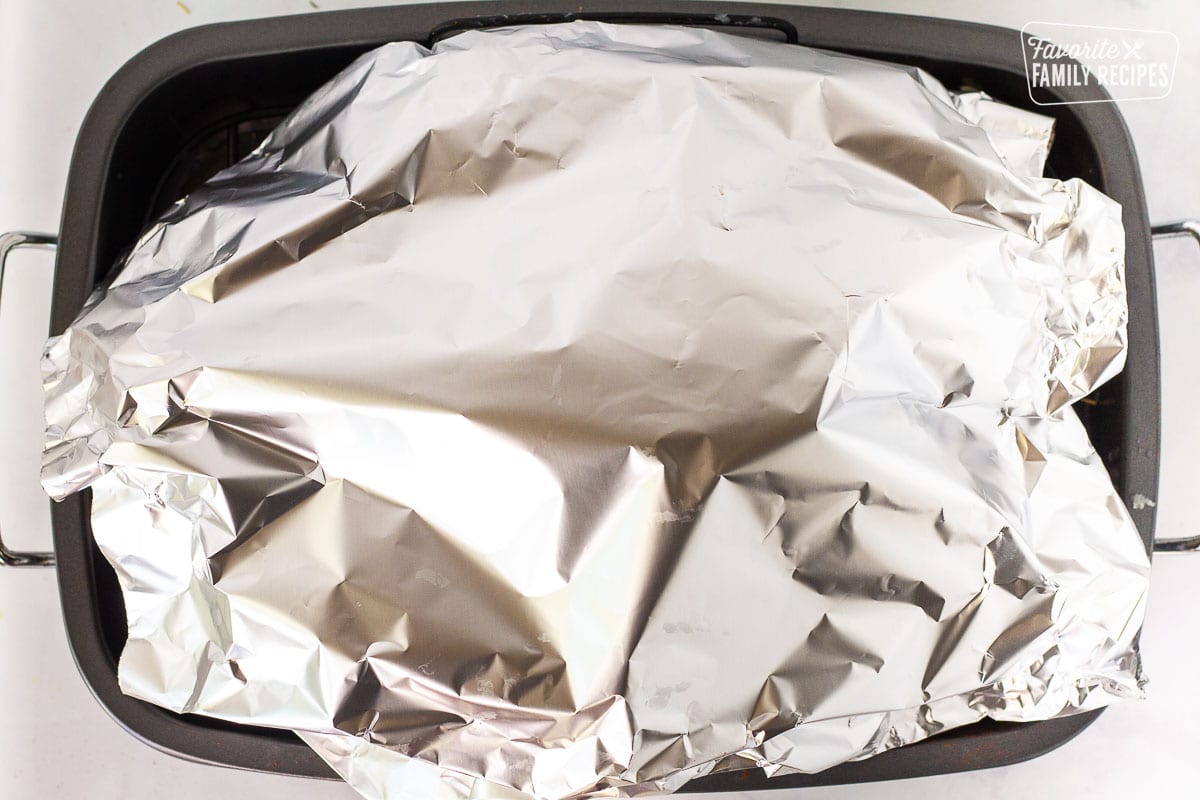 Turkey covered with foil in a roasting pan for How to Cook a Turkey.