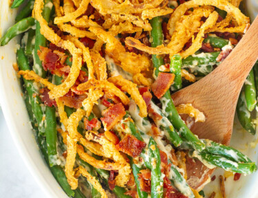 Dish of Green Bean Casserole with a wooden spoon.