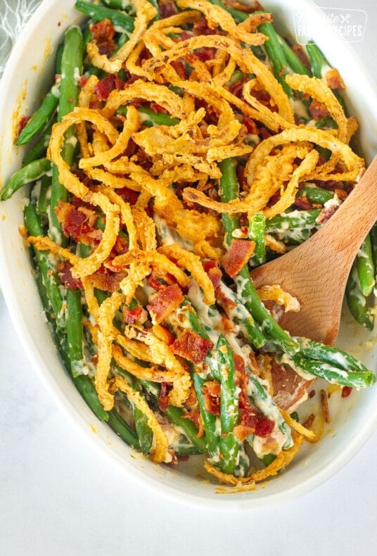 Dish of Green Bean Casserole with a wooden spoon.