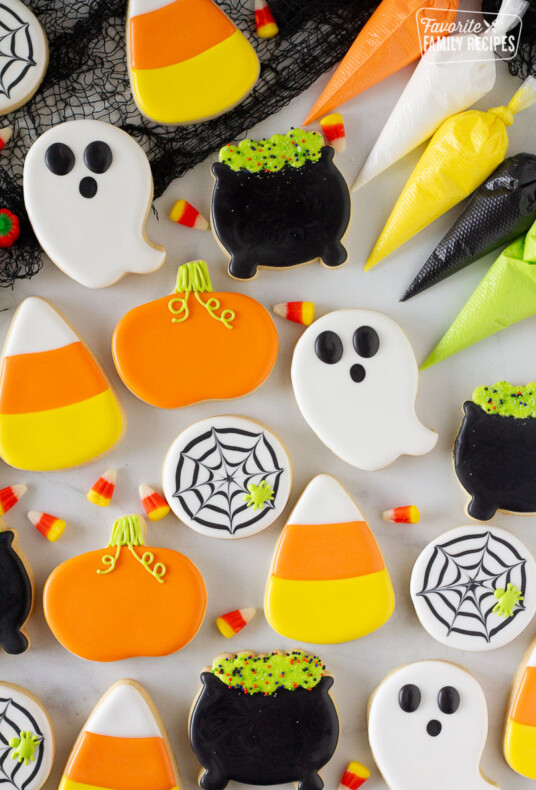Ghosts, cauldron, spider web, pumpkin and candy corn Halloween Cookies. Piping bags of icing on the side.