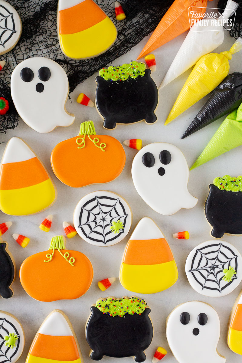 Ghosts, cauldron, spider web, pumpkin and candy corn Halloween Cookies. Piping bags of icing on the side.