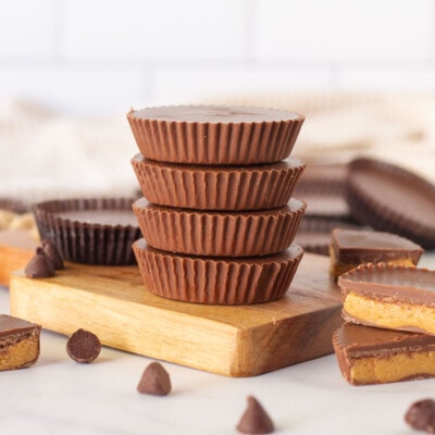 Stack of Homemade Reese's Peanut Butter Cups surrounded by Reese's Peanut Butter Cups.