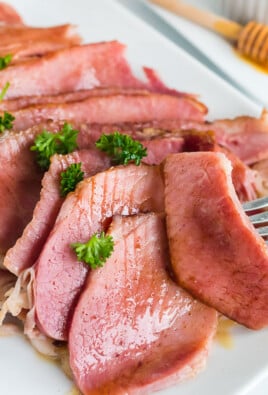 Slices of honey baked ham on a plate with a fork