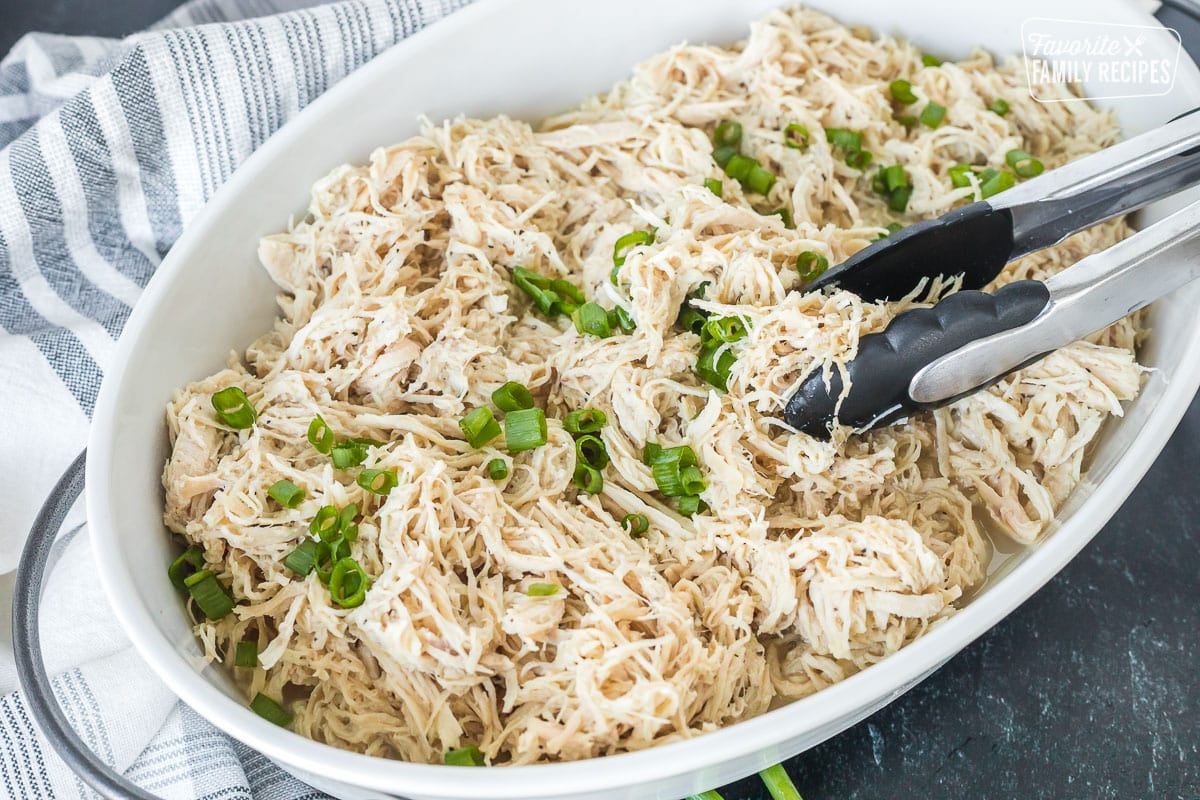 A dish with shredded chicken and tongs