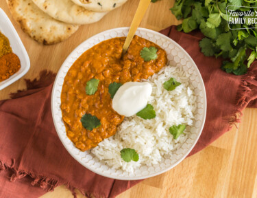 Lentil curry in a bowl with rice topped with cilantro and plain yogurt