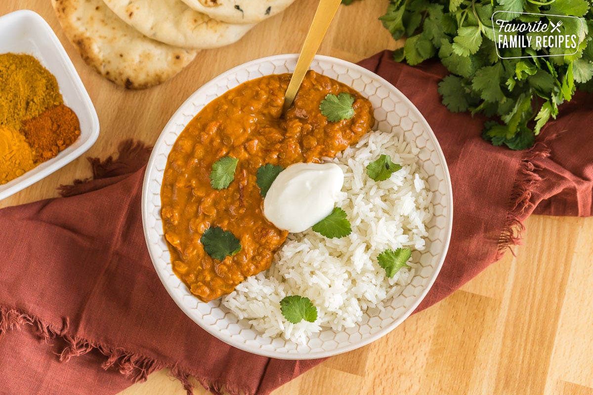 Lentil curry in a bowl with rice topped with cilantro and plain yogurt