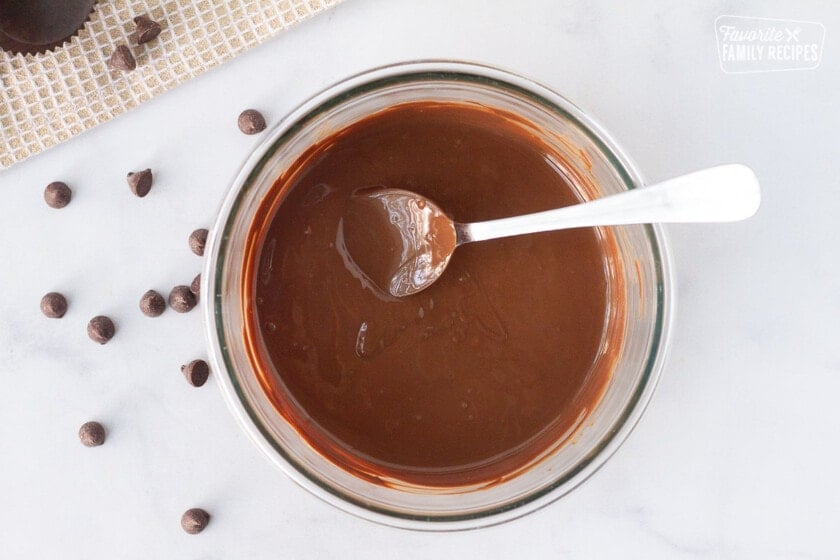Bowl of melted chocolate with a spoon for Homemade Reese's Peanut Butter Cups.