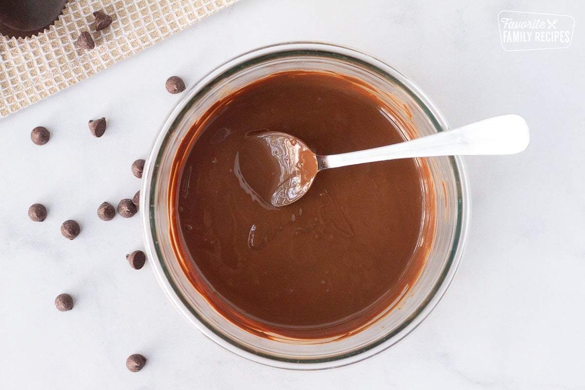 Bowl of melted chocolate with a spoon for Homemade Reese's Peanut Butter Cups.