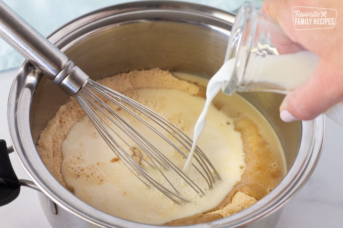 Milk pouring into pan of dry ingredients with whisk to make Butterscotch Pie filling.