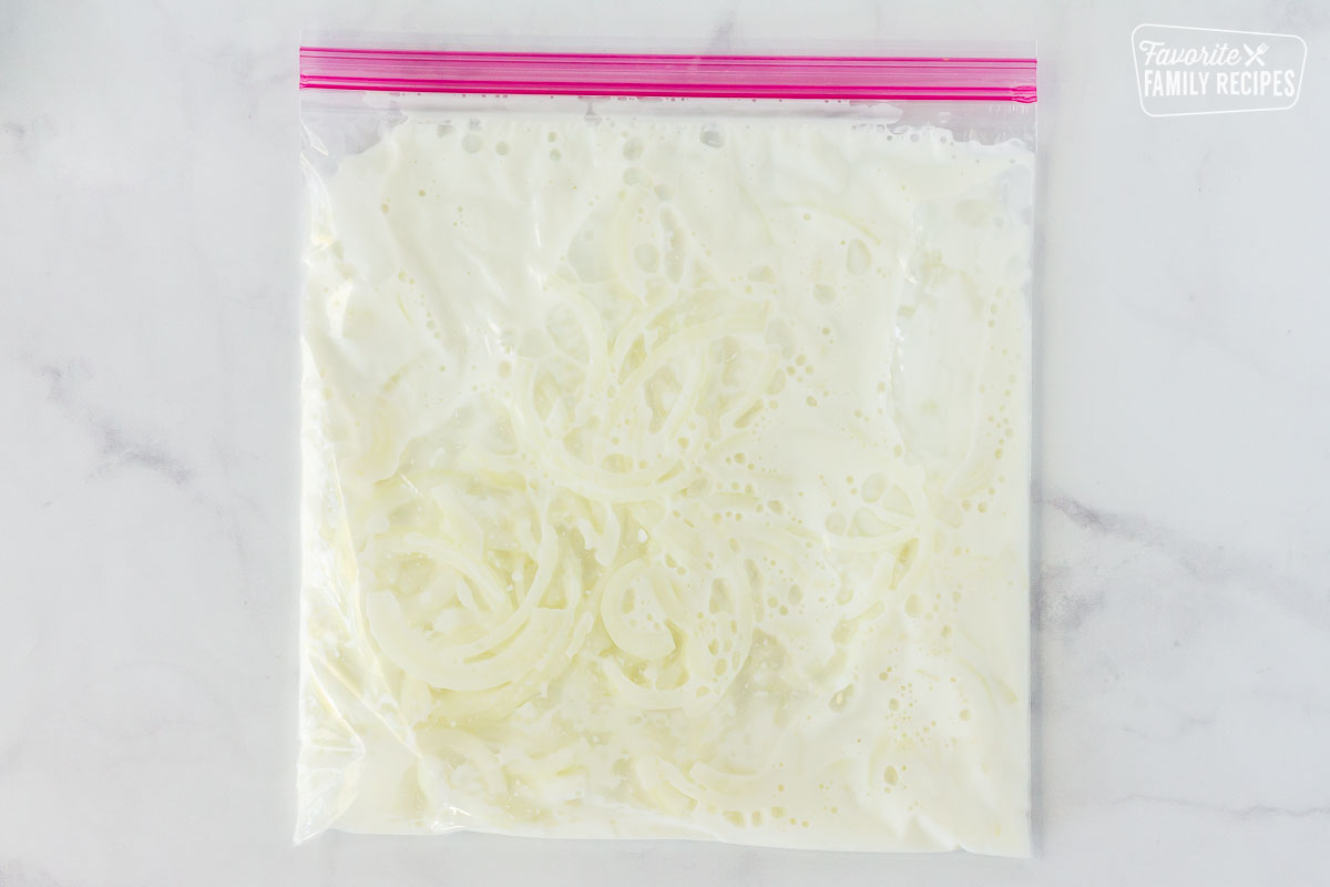 Sliced onions and buttermilk in a Ziplock bag for Green Bean Casserole topping.
