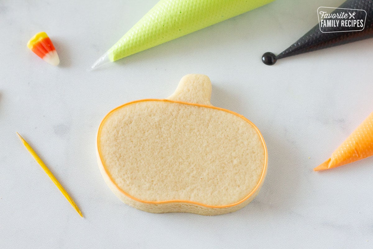 Pumpkin Halloween Cookie with orange royal icing outline.