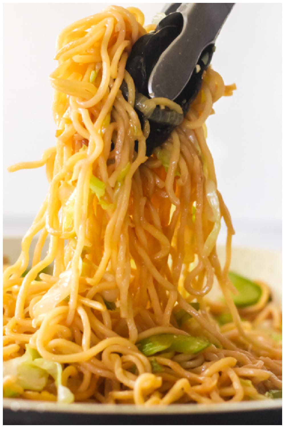 Tongs pulling up Panda Express chow mein noodles from a pan to show length