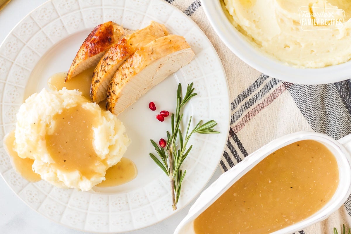 Top view of a plate with mashed potatoes, turkey and gravy with Turkey Gravy and mashed potatoes on the side.