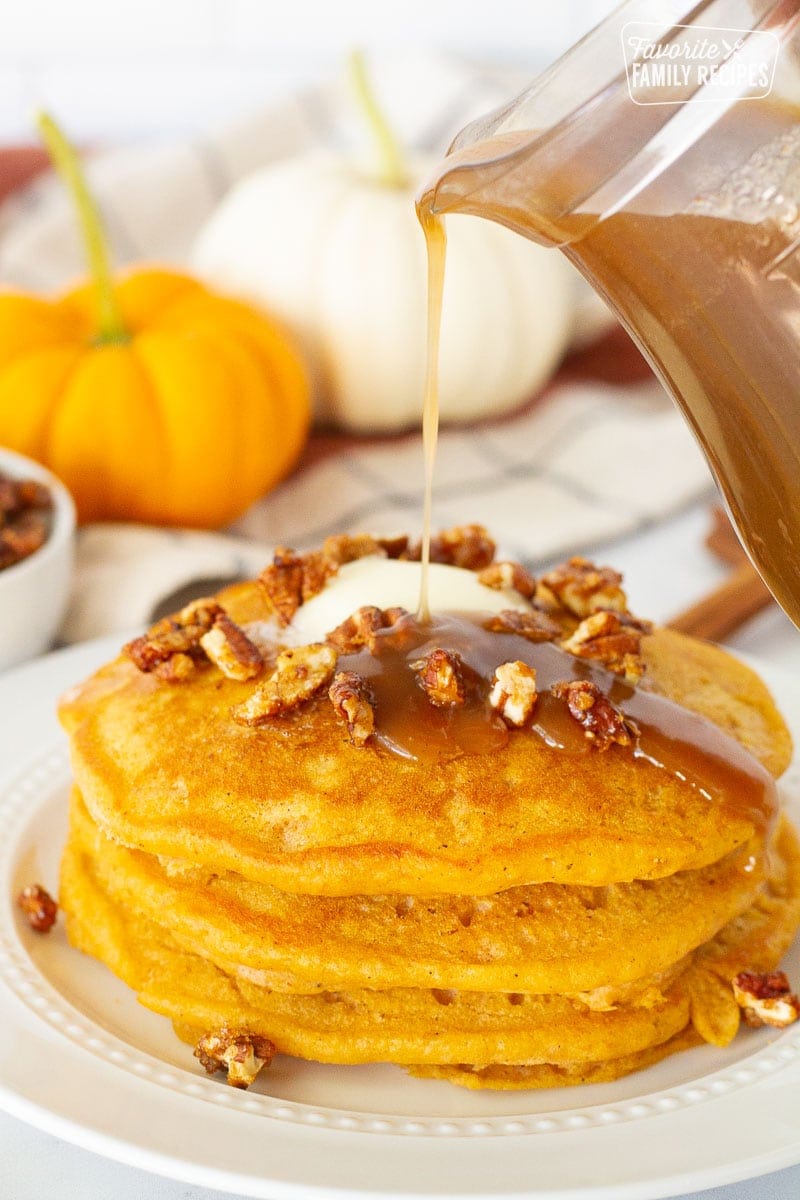 A stack of pumpkin pancakes with caramel syrup.