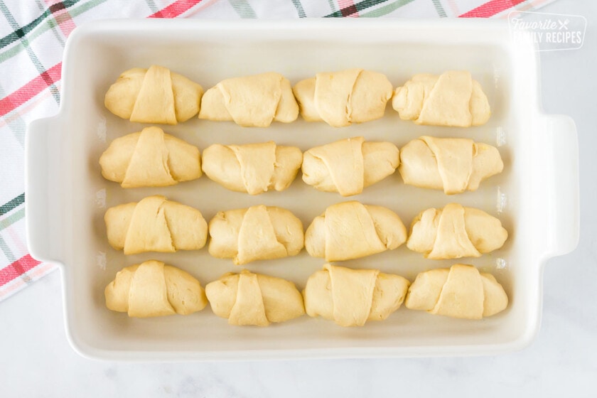 Twelve rolled Apple Dumplings ins a baking dish.