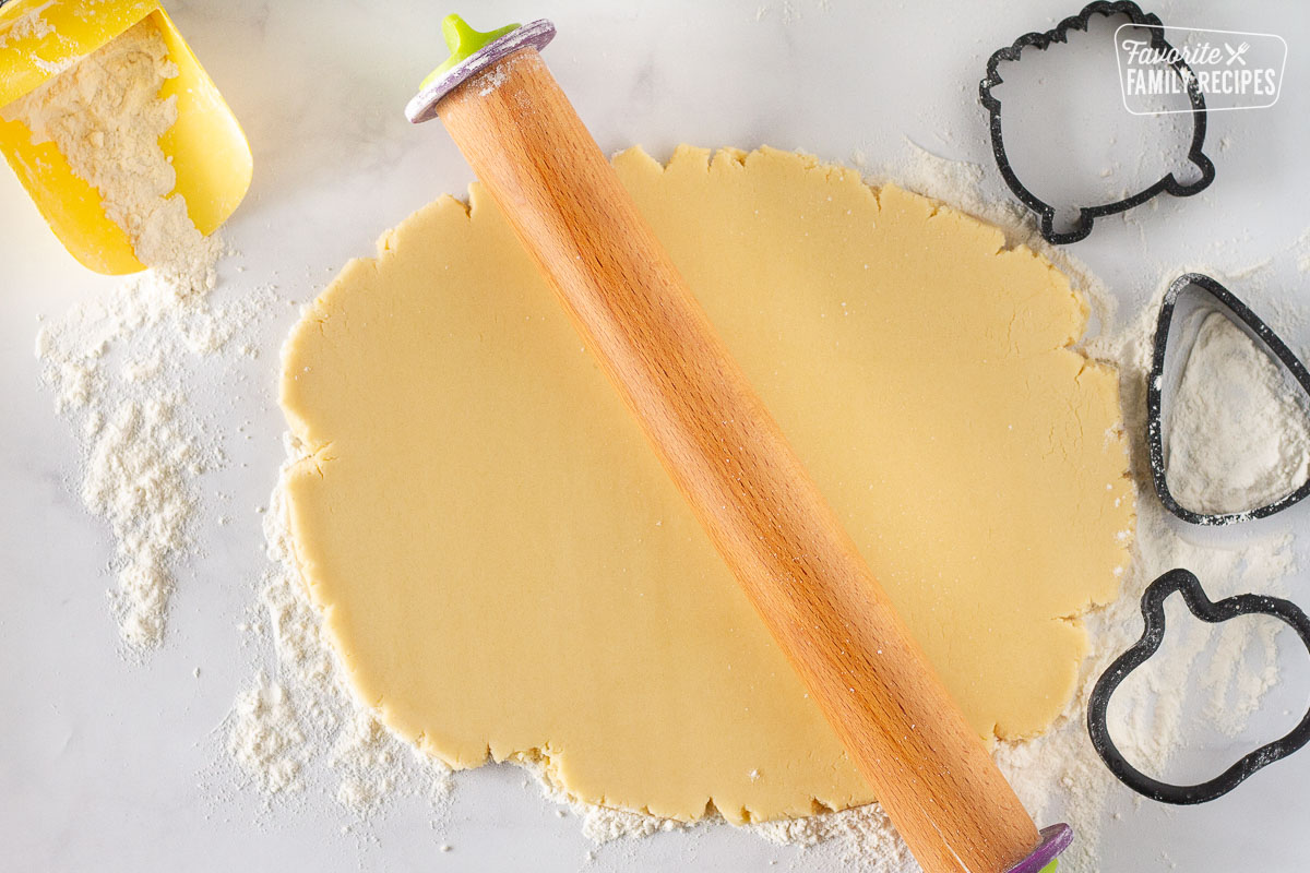 Rolled out cookie dough with a wooden rolling pin for Halloween Cookies.