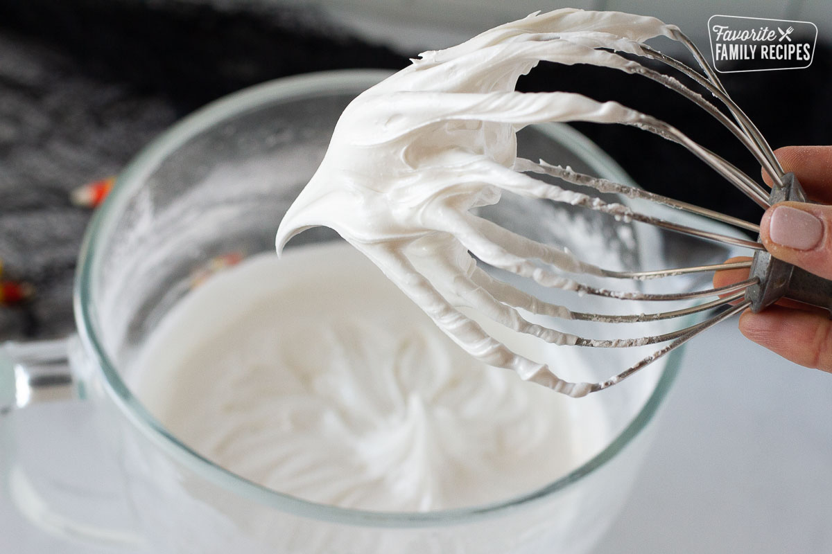Whisk holding freshly whipped Royal Icing with a stiff peak to make Halloween Cookies.