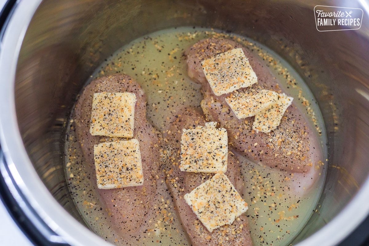 Chicken in an Instant Pot with broth, butter, and seasonings.