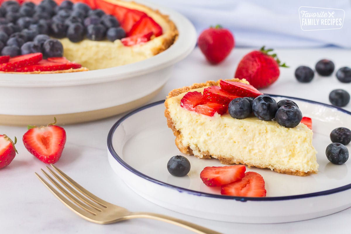 Slice of cheesecake on a plate with fruit for How to Make a Cheesecake.