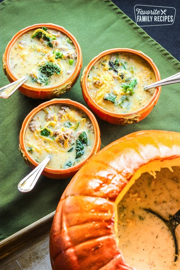 Soup in a pumpkin with three pumpkin bowls with i
