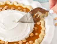 Serving spatula slicing into a Butterscotch Pie. Plates and forks in the background.
